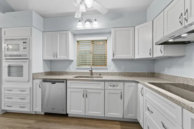 a kitchen with granite countertop a sink cabinets stainless steel appliances and a window