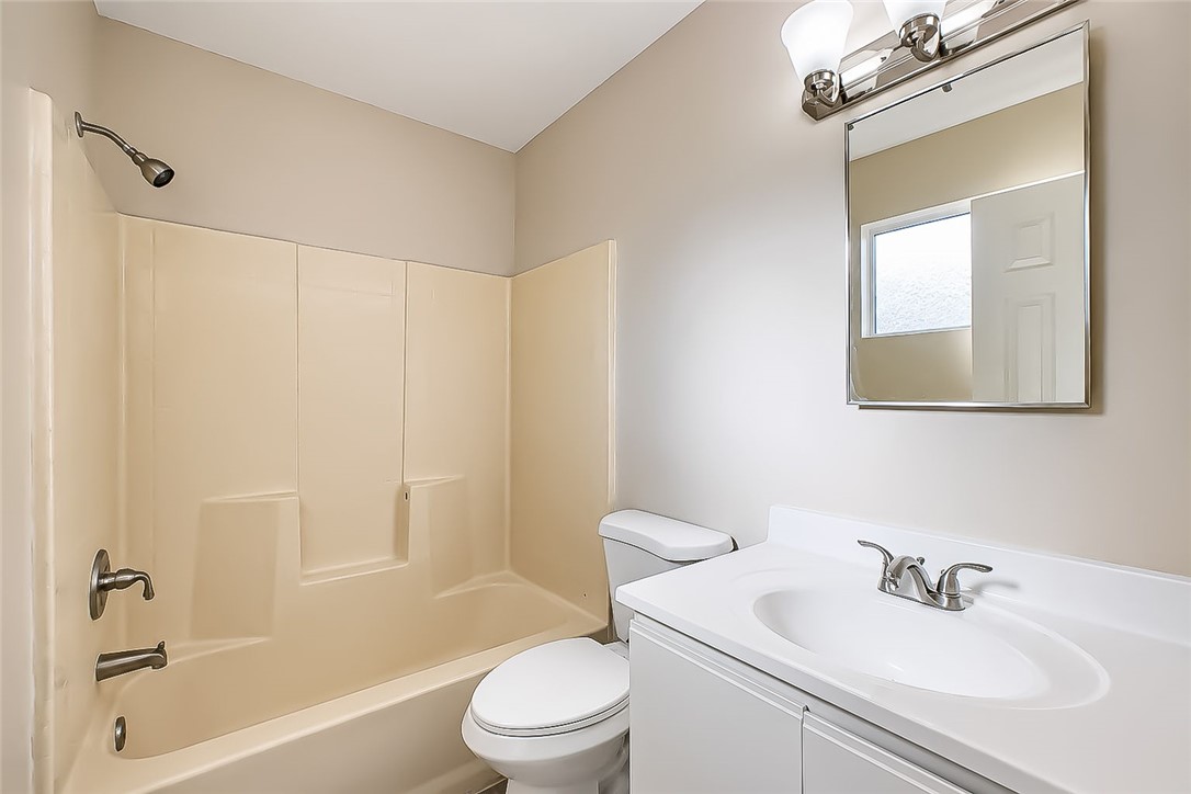 1720 Valencia Road Fort Mohave, AZ 86426 - Photo 31 of 32 Full bathroom featuring a tub/shower combination with a bronze-finish showerhead, a white vanity with an integrated sink, a chrome-finish faucet, and a rectangular wall mirror with an overhead vanity light