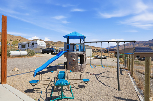 1588 West Rim Rock Drive Stockton, UT 84071 - Photo 38 of 61 Outdoor play structure featuring a slide, swings, and a seesaw, set on a gravel surface