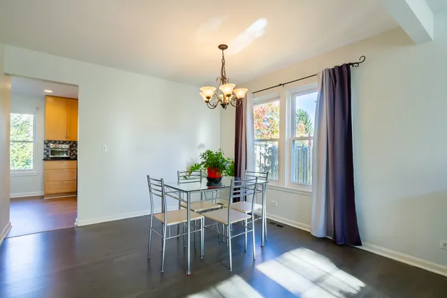 a dining room with wooden floor a chandelier a glass table and chairs