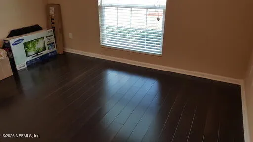 a view of an empty room with wooden floor and a window