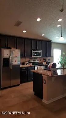 a kitchen with stainless steel appliances granite countertop a refrigerator a sink a stove a microwave and wooden cabinets