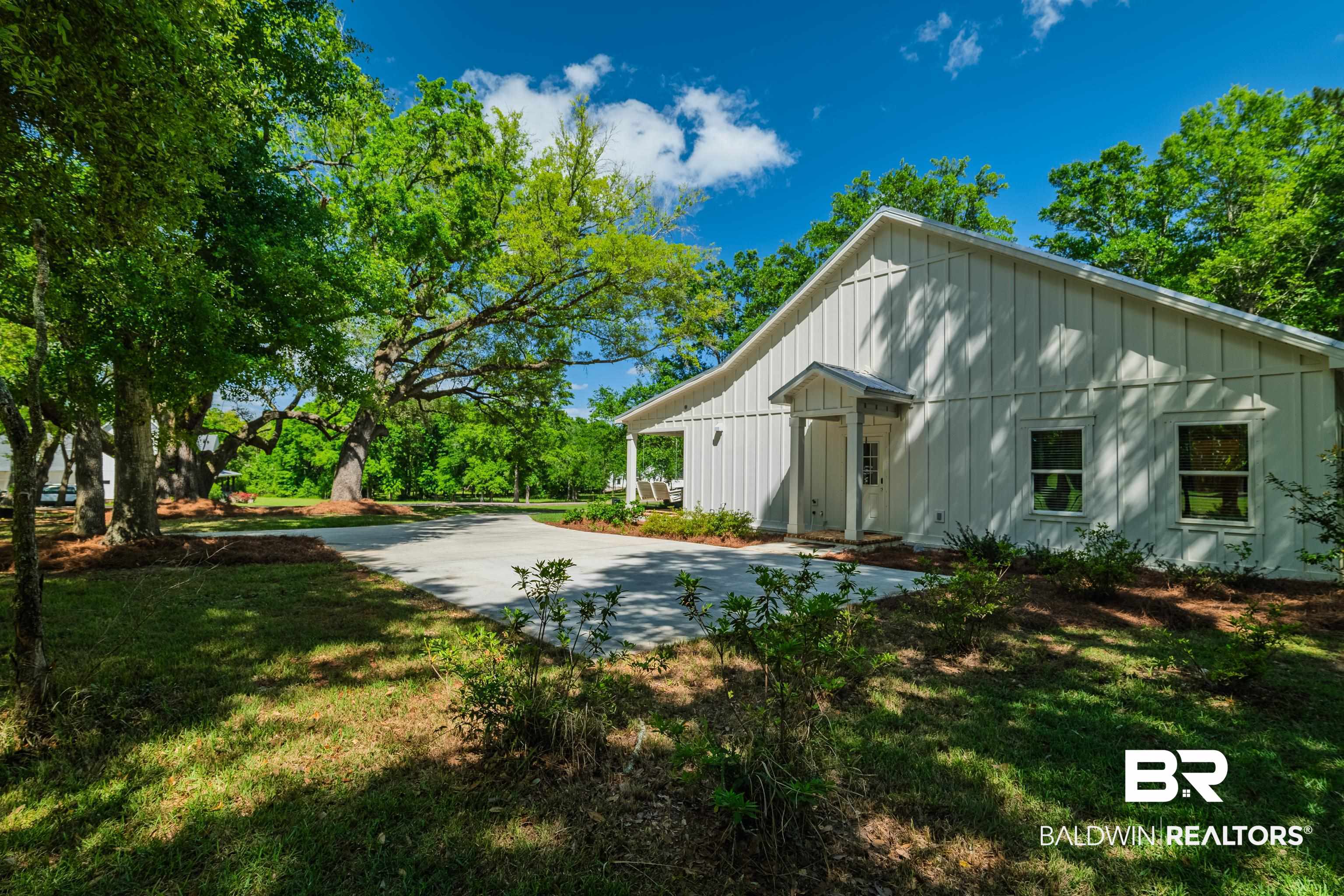 19121 Boothe Road Fairhope, AL 36532 - Photo 30 of 41 Rear view of house featuring board and batten siding and a yard