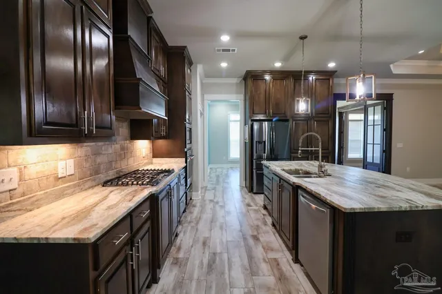 a kitchen with stainless steel appliances granite countertop a stove a refrigerator and a sink