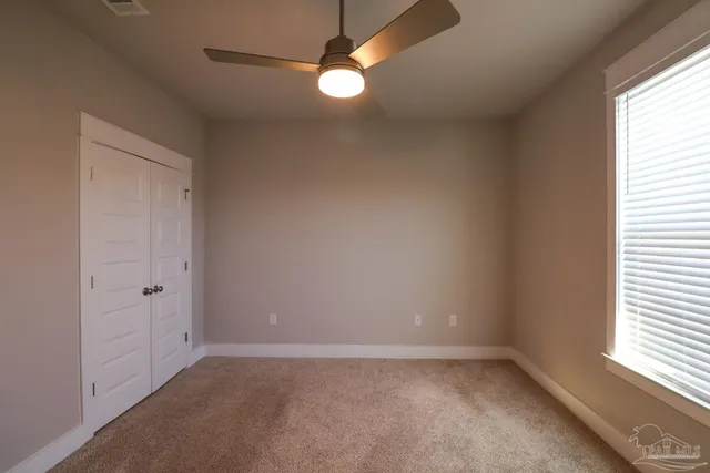 an empty room with windows and fan
