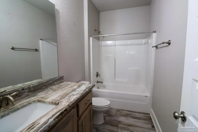 a bathroom with a granite countertop sink toilet a shower and a mirror
