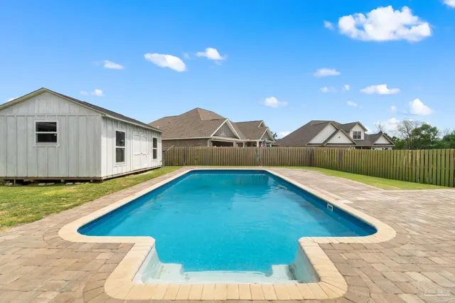 a view of a house with swimming pool and wooden fence