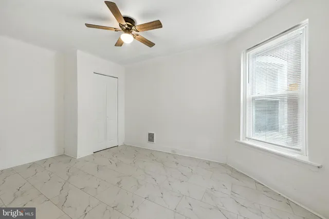 an empty room with windows and fan