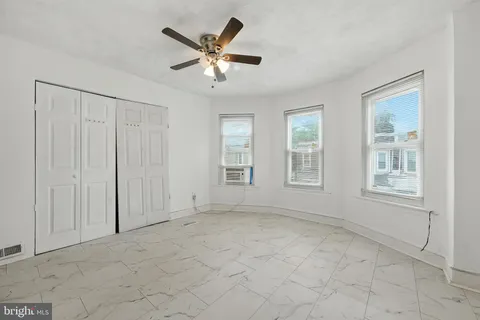 an empty room with windows and fan