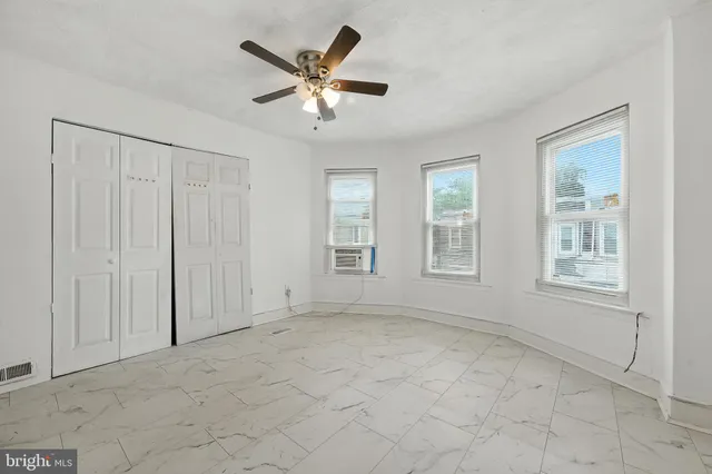 an empty room with windows and fan