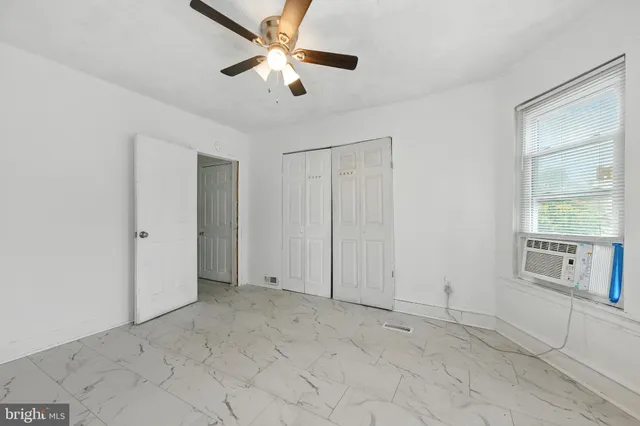 an empty room with chandelier fan and windows