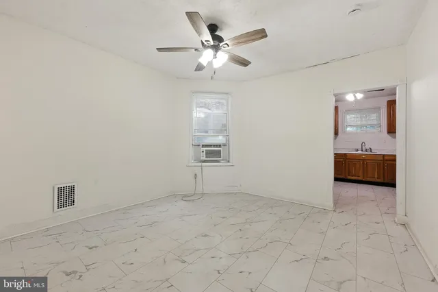 an empty room with chandelier fan and windows