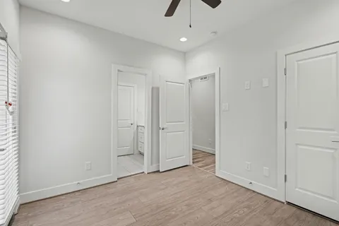 an empty room with wooden floor and ceiling fan