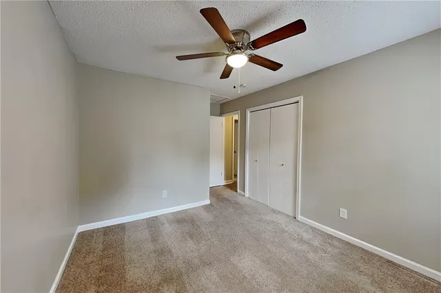an empty room with closet and ceiling fan