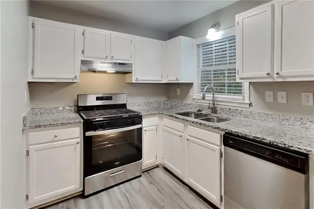 a kitchen with granite countertop white cabinets and appliances
