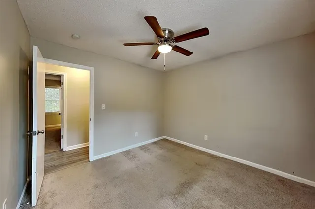 an empty room with closet and a ceiling fan