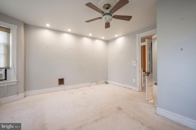 an empty room with ceiling fan and windows