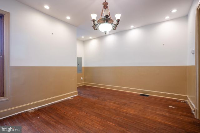 an empty room with wooden floor and chandelier fan