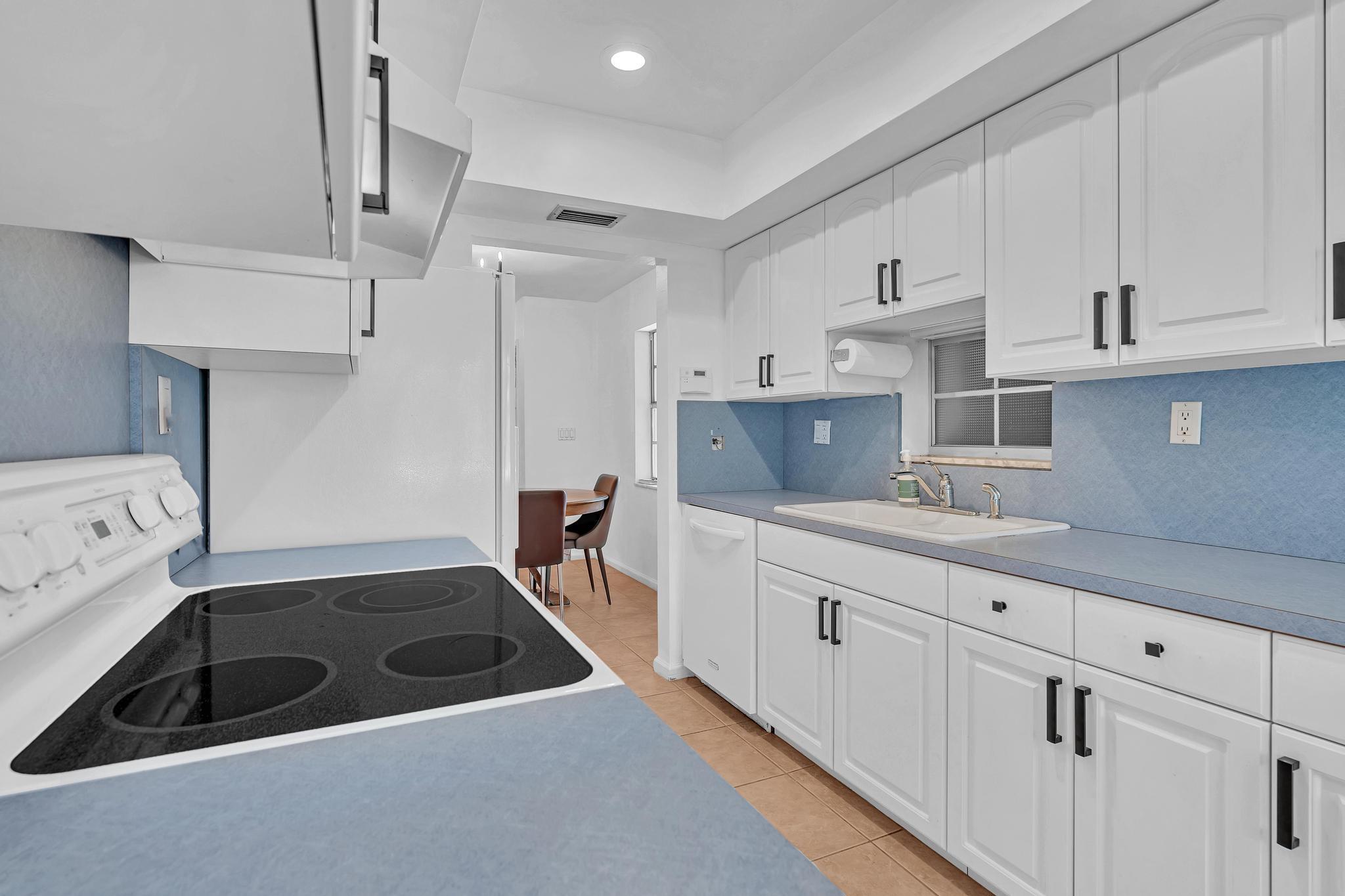 313 Northwest 42nd Street Boca Raton, FL 33431 - Photo 13 of 42 a kitchen with white cabinets and sink