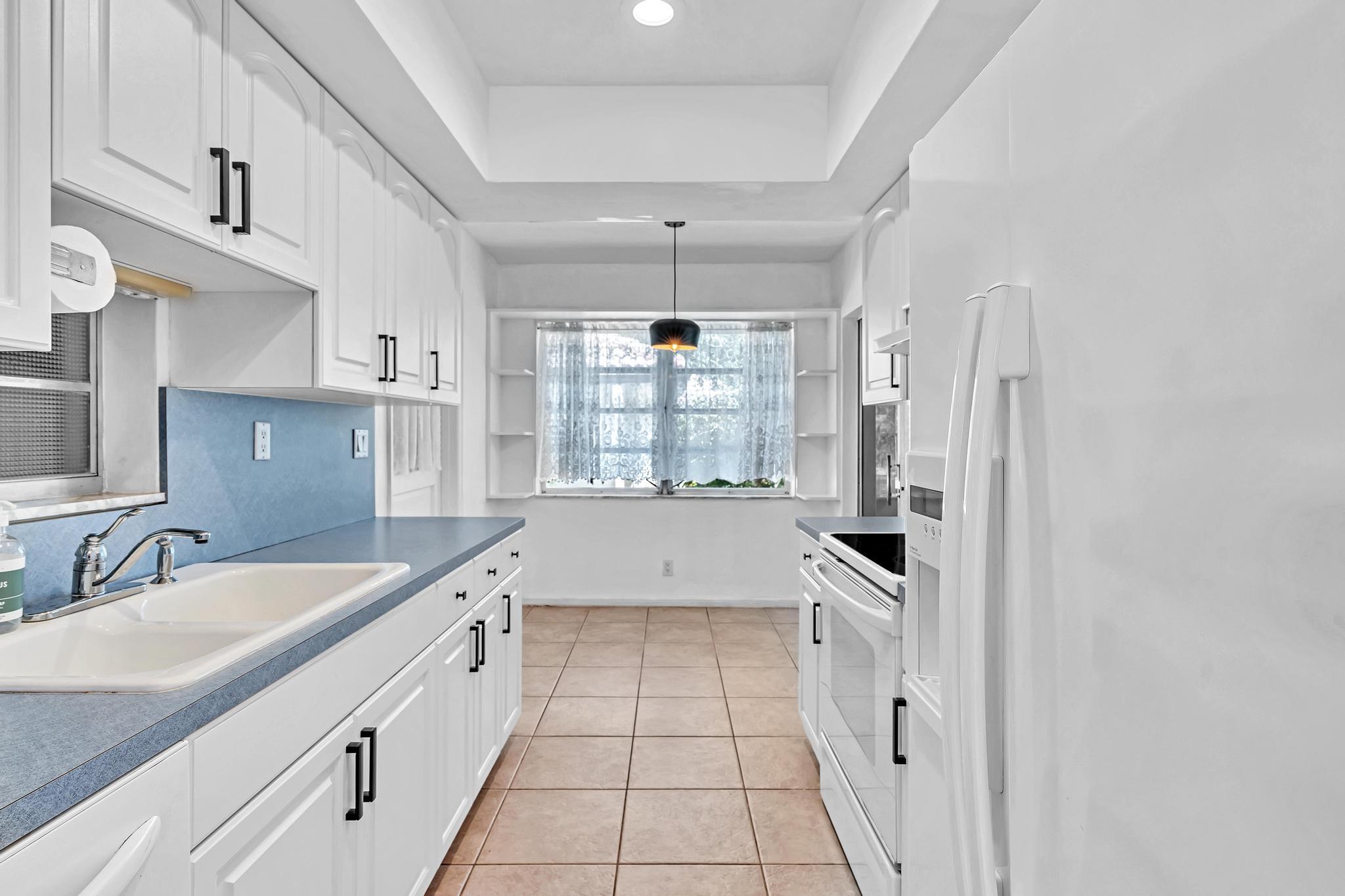 313 Northwest 42nd Street Boca Raton, FL 33431 - Photo 6 of 42 a large white kitchen with granite countertop a sink and dishwasher a stove with wooden floors