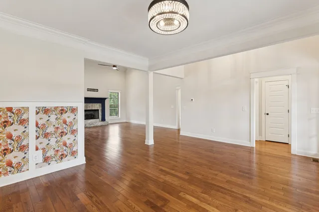 an empty room with wooden floor fireplace cabinet and windows