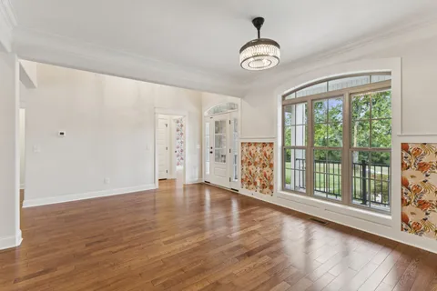 a view of an empty room with wooden floor a fireplace and a window