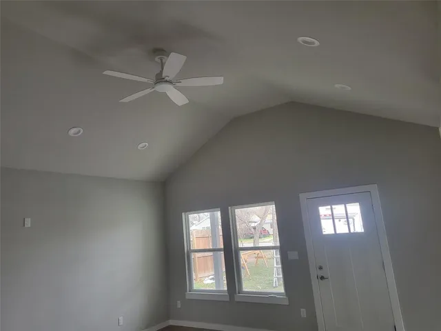 an empty room with windows and ceiling fan