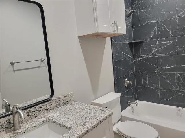 a bathroom with a granite countertop sink toilet and shower