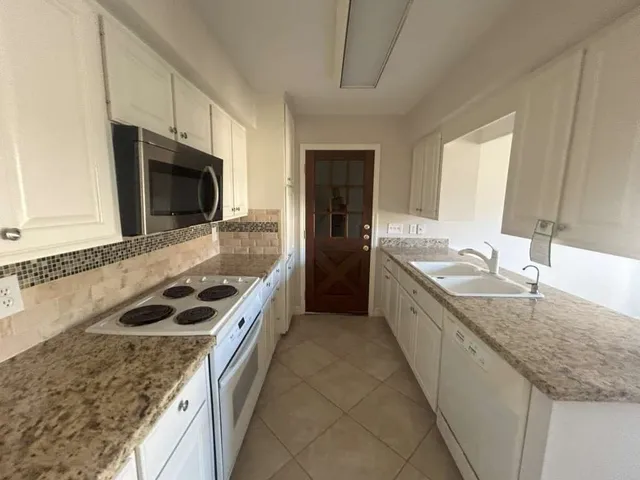 a large kitchen with a sink and a stove top oven with wooden floor