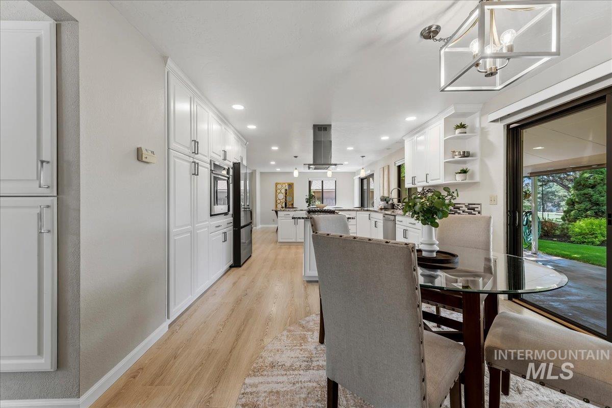 599 Pebble Beach Way Eagle, ID 83616 - Photo 14 of 44 Spacious kitchen featuring extensive white cabinetry, wood-finish flooring, recessed lighting, and a modern range hood