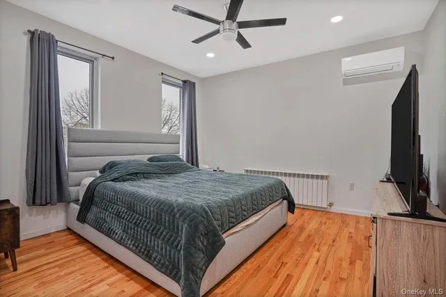 a bedroom with a bed tv and wooden floor