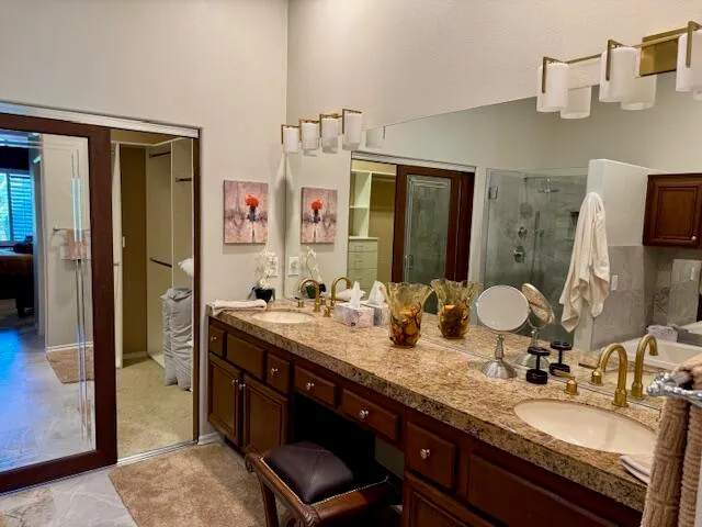 a bathroom with a granite countertop sink a mirror and shower