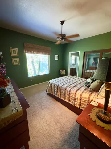 a bedroom with a bed ceiling fan and a window