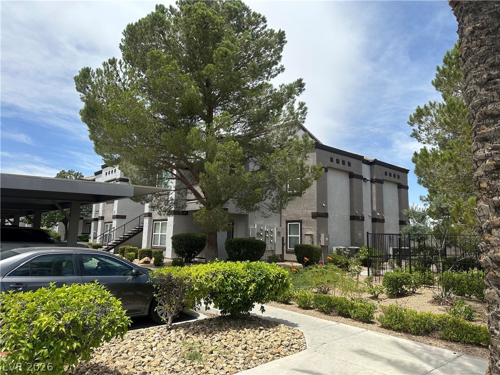 7255 West Sunset Road, Unit 2006 Las Vegas, NV 89113 - Photo 4 of 24 Mature trees frame this multi-level residential building with well-maintained landscaping and covered parking.