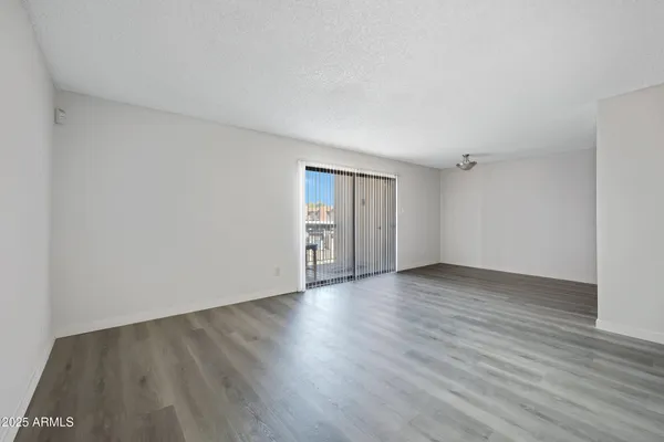 a view of an empty room with wooden floor and closet
