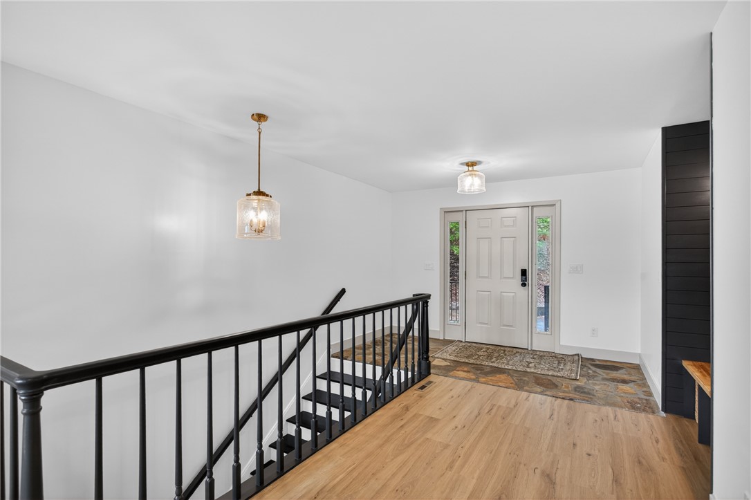 304 Lakeside Drive Seneca, SC 29672 - Photo 3 of 50 A welcoming entryway with a wood-look floor transitions to a stone landing at the front door, complemented by a sleek black staircase.