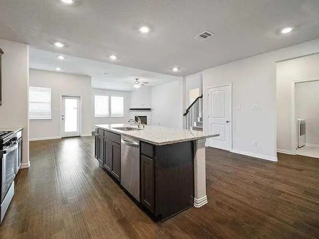 an open kitchen with wooden floor and stainless steel appliances