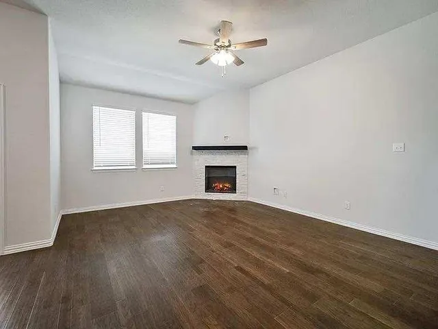 an empty room with wooden floor fireplace and windows