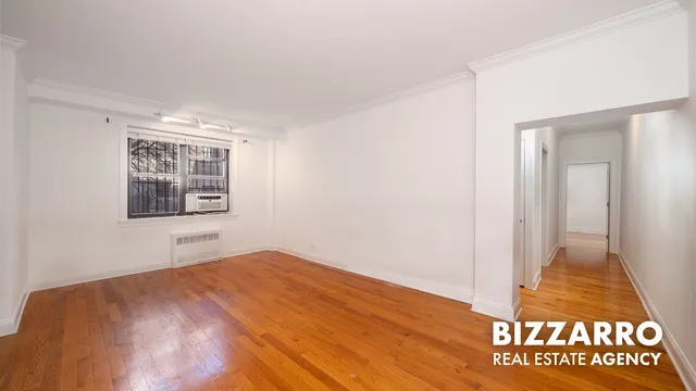 a view of an empty room with window and wooden floor