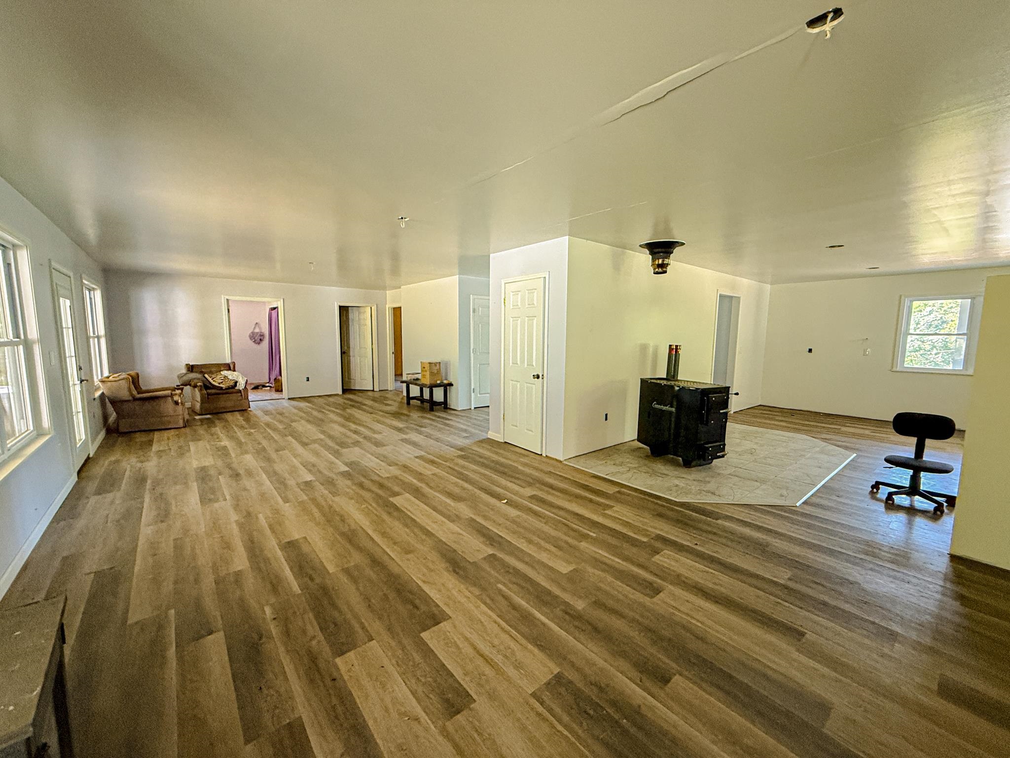 1421 Copper Spring Road Springville, TN 38256 - Photo 12 of 40 Wood-finish flooring throughout, white walls, and a built-in wood stove on a tiled hearth