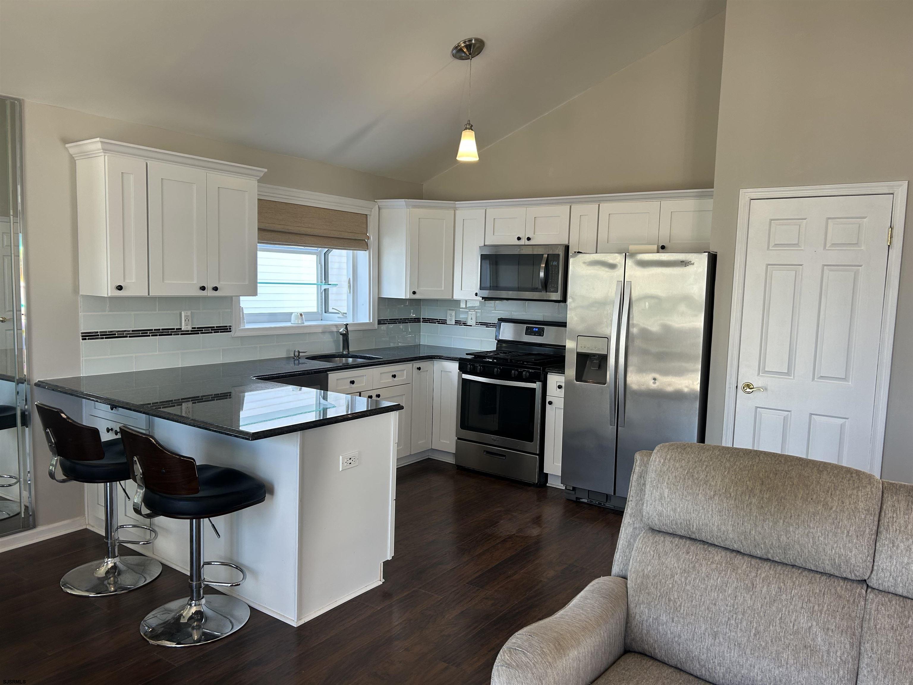 12 Vardon Road Brigantine, NJ 08203 - Photo 7 of 28 a kitchen with kitchen island granite countertop wooden floors and stainless steel appliances