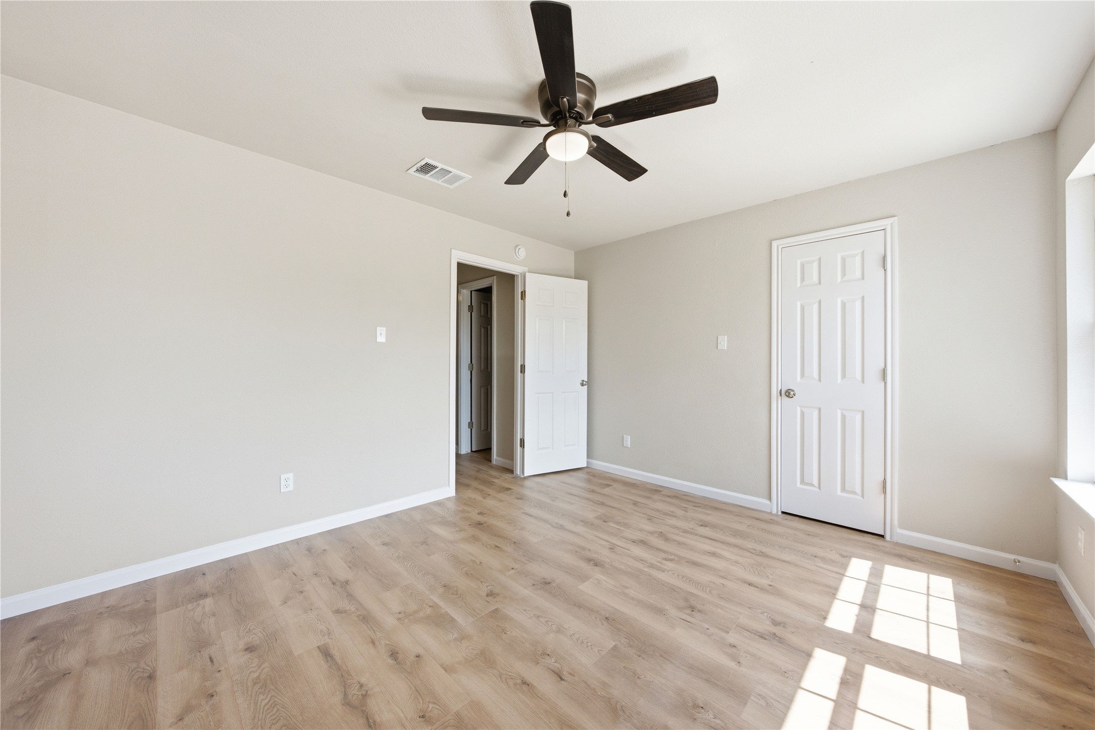 6917 Panda Royle Drive Del Valle, TX 78617 - Photo 21 of 23 A well-lit bedroom features durable laminate flooring and a ceiling fan for year-round comfort.