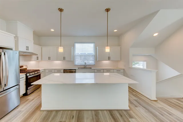 a large kitchen with kitchen island a stove a sink a center island and wooden floor