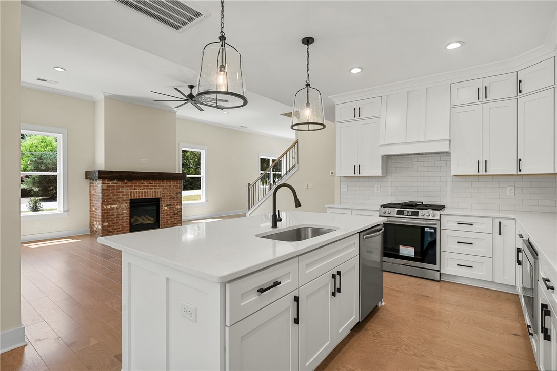 100 Garden Gate Drive Anderson, SC 29621 - Photo 16 of 43 This open concept living space features a modern kitchen, a brick fireplace, and gleaming hardwood floors.