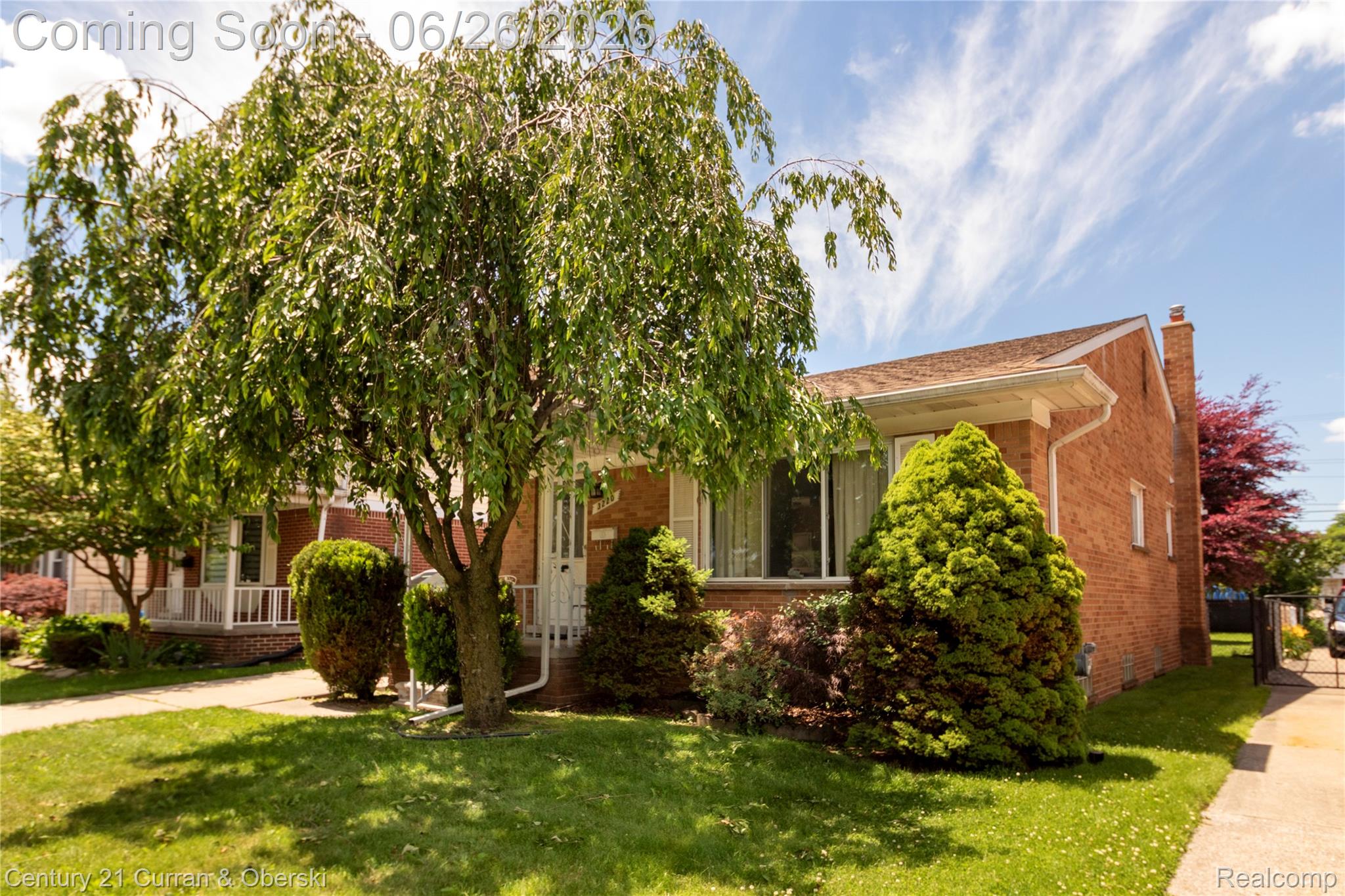 3220 Alice Street Dearborn, MI 48124 - Photo 2 of 39 Brick exterior home featuring a front porch with white railings, a weeping deciduous tree, and manicured evergreen shrubbery