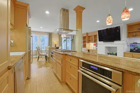 a large living room with stainless steel appliances furniture a fireplace and a flat screen tv