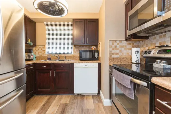 a kitchen with a sink a stove cabinets and a wooden floor