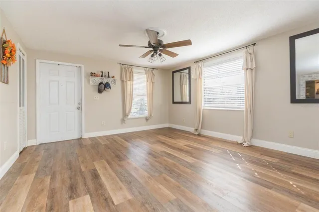 a view of empty room with wooden floor and fan