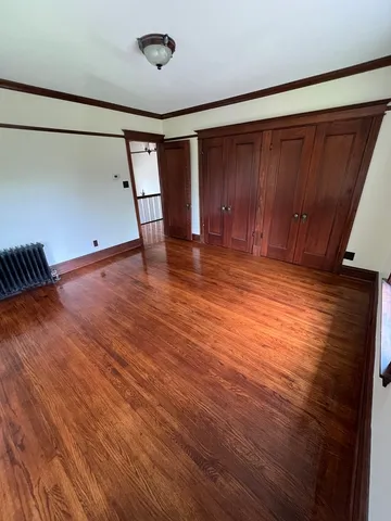 a view of an empty room with wooden floor and stairs