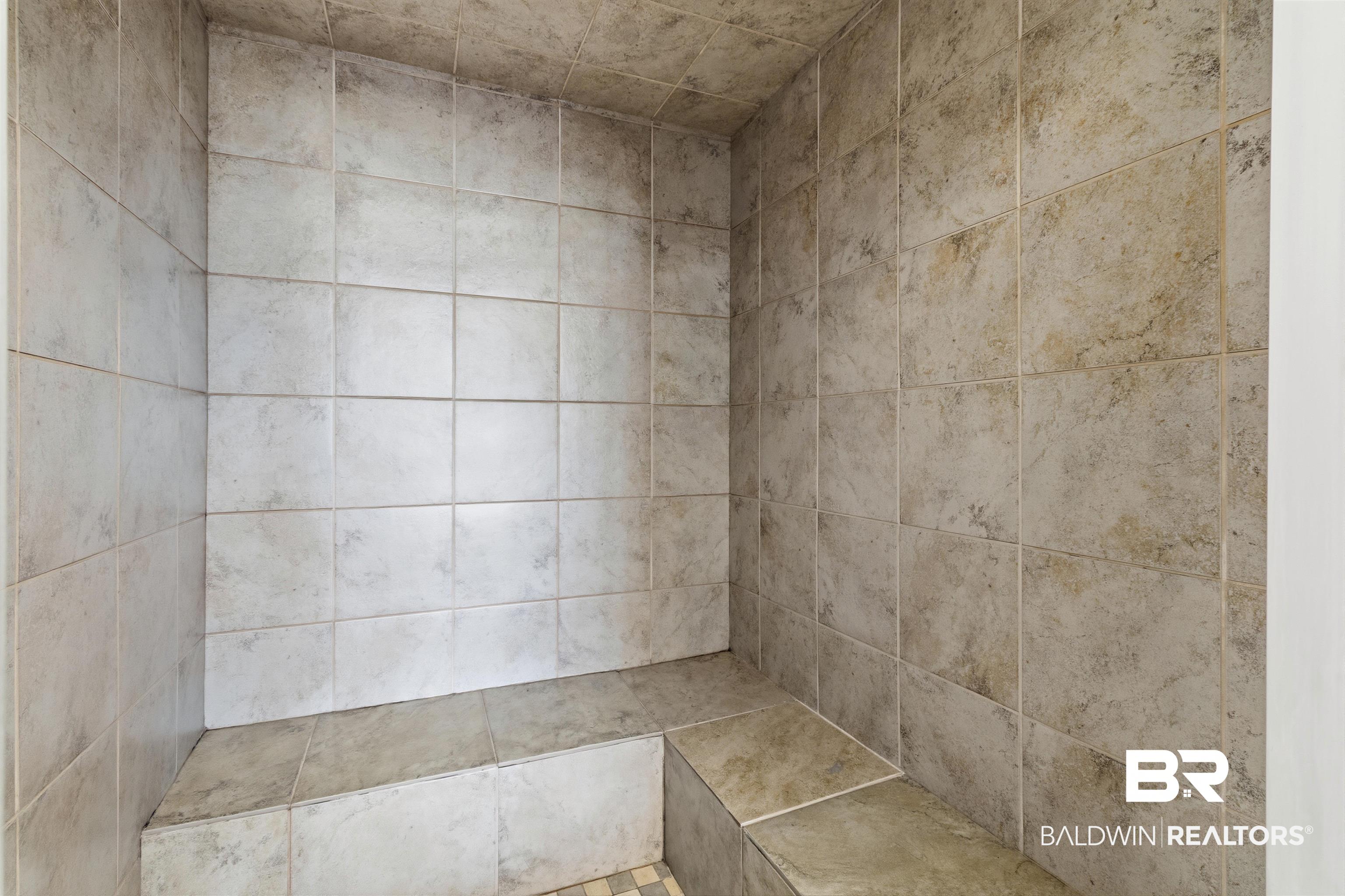 3564 Bayou Road, Unit 203 Orange Beach, AL 36561 - Photo 32 of 53 Tiled shower enclosure featuring light-toned square wall tiles and a built-in tiled bench